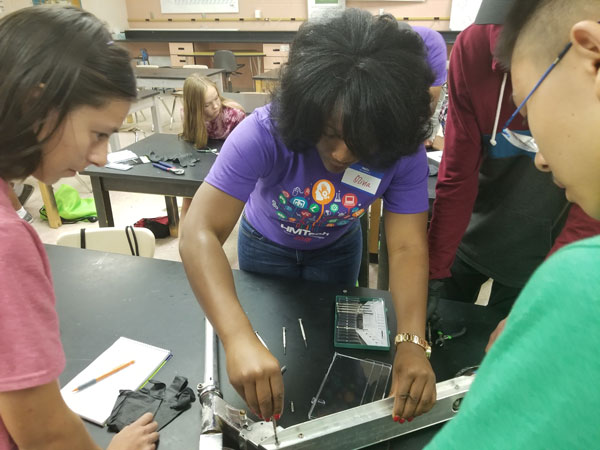 Olivia helps students disassemble a scooter