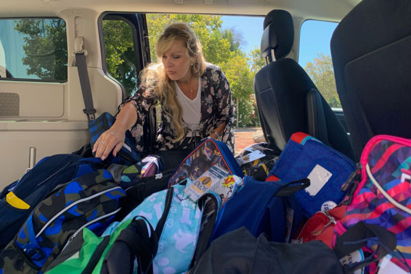 volunteer loads SUV with backpacks to donate