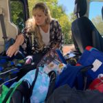 volunteer loads SUV with backpacks to donate