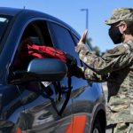airman hands backpack through vehicle window