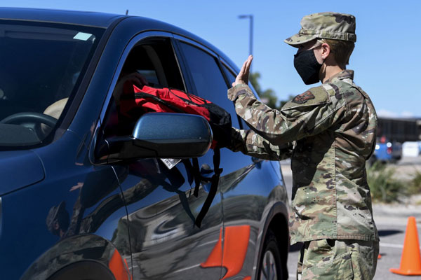 airman hands backpack through vehicle window