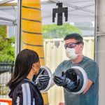 medical worker tests patient from inside portable testing booth