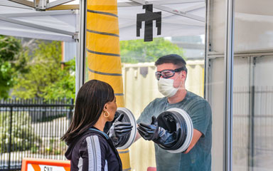 medical worker tests patient from inside portable testing booth