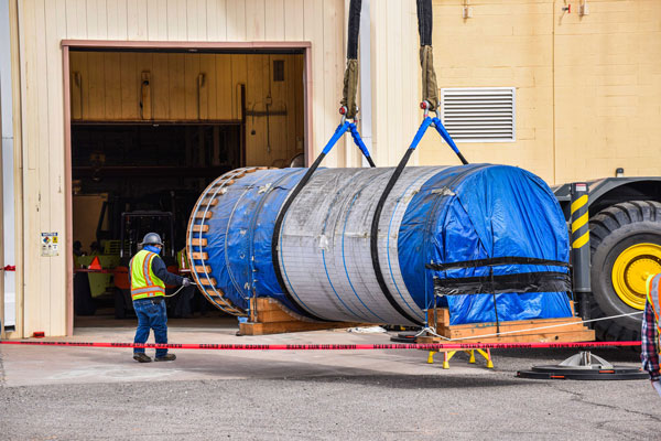 giant steel canister being loaded into warehouse