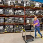 Michael Somuk wheels cart through computer warehouse