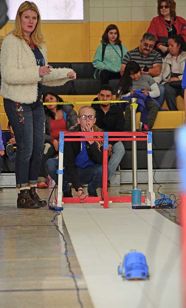 Katrina Wagner (left), a community relations specialist and Sandia volunteer, prepares to write down the time during the first heat of races during the New Mexico Electric Car Challenge. More than 150 middle school students from across New Mexico participated in the challenge, presented by Sandia National Laboratories, Los Alamos National Laboratory, PNM and Intel.   The challenge, held Nov. 19 at Albuquerque’s Van Buren Middle School, is an annual STEM event in its 10th year. Students formed 5-person teams at the beginning of the school year and were provided basic materials—a lithium-ion battery, a direct-current motor, and other materials such as a chassis and wheels—needed to build their cars.  “Our goal is to expose students to basic engineering. This allows them to see how math and science intersect,” said Amy Tapia, Sandia’s community relations manager.  The teams were also required to give oral presentations on the designs of their cars, as well as the challenges they faced while constructing and running them.