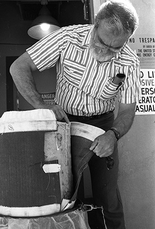 Karl Schuler (DMTS, 1522) looks at a propellant bag of the type involved in the USS Iowa incident. The dark material is a wear-saving cover; the lighter, laced bag inside is the silk propellant bag; Vol. 42, No. 12, Page 12 Get info for 90066 - Karl Schuler (DMTS, 1522) looks at a propellant bag of the type involved in the USS Iowa incident. The dark material is a wear-saving cover; the lighter, laced bag inside is the silk propellant bag; Vol. 42, No. 12, Page 12