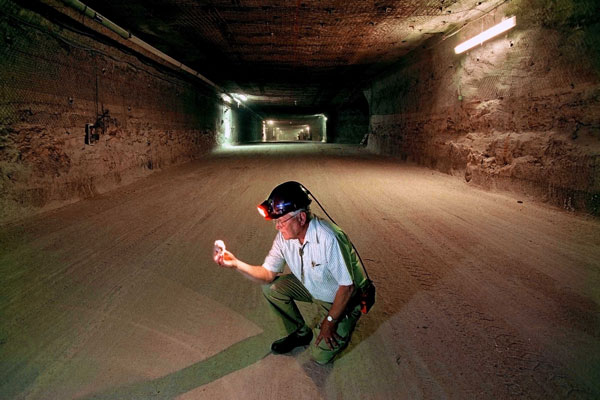 Wendell Weart in hard hat kneels in giant underground tunnel