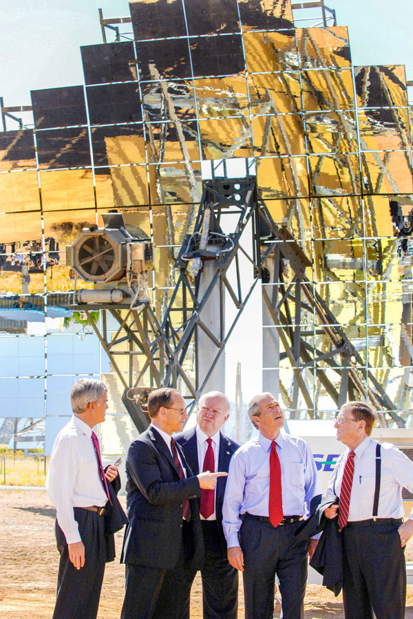 group of men stands talking outside solar tower