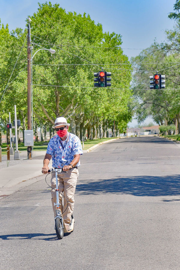 employee rides scooter to work wearing mask