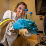 scientist compares test tubes in anaerobic glovebox