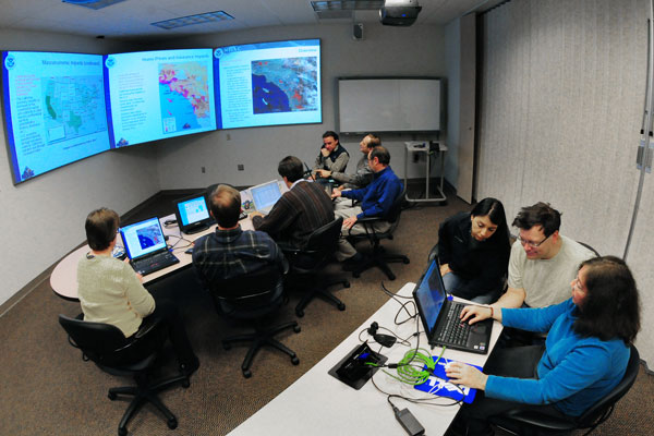 people in conference room looking at data on monitors