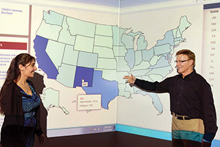 Pete Atherton, senior manager of Industry Partnerships Dept. 1930, goes over New Mexico information on the Partnerships National Reach Map with software developer Lozanne Chavez (1931). The map shows the numbers and types of Sandia partnership agreements across the country.	(Photo by Randy Montoya)