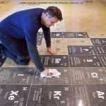 Man polishing periodic table inlaid on museum floor