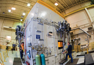REMOTE CONTROL — Mike Torneby (1387) and Dave Siddoway (1387) use remote manipulators to maneuver materials inside the Auxiliary Hot Cell Facility in Tech Area 5. (Photo by Randy Montoya)