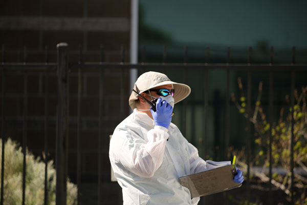 employee outside medical clinic in PPE talking on walkie talkie