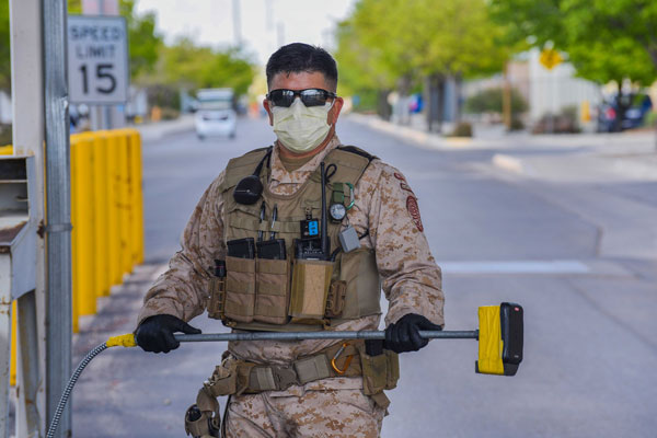 officer at gate holding badge reader on extension pole