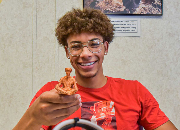 student holds up 3D figure of himself