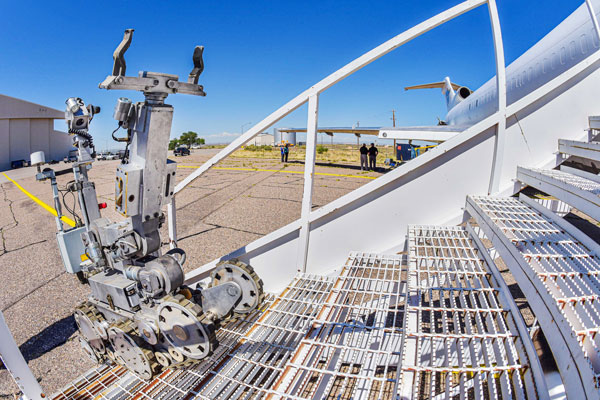 A robot climbs stairs to the cabin of a cargo plane