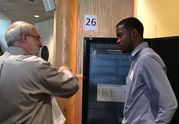 Isaiah Grigsby (9315), a summer undergraduate intern from Clark Atlanta University, explains his cybersecurity poster.   (Photo by Mollie Rappe)