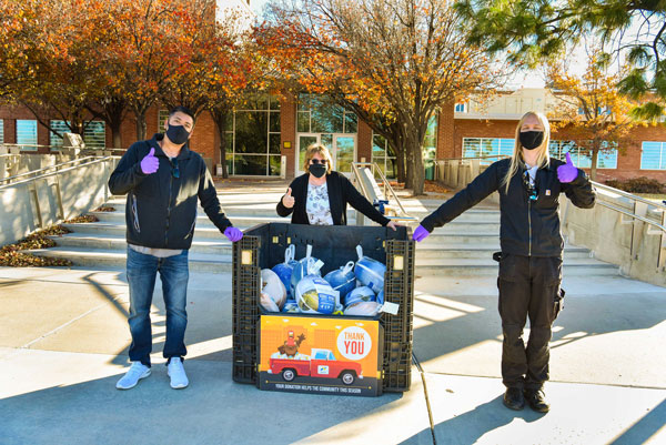 volunteers stand next to turkey collection bin