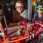 engineers observe laser that records measurements in wind tunnel
