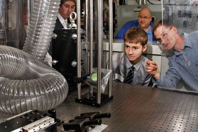 In the alternative fuels lab, Chuck Mueller shows LHS student Aaron Costello a window in the piston of a single-cylinder, heavy-duty diesel engine that has been modified to provide optical access to the combustion chamber. Academy teacher Mike Waltz looks on from across the lab.	(Photo by Randy Wong)