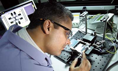 TINY BUT GRAND — Ken Patel works on the digital microfluidic hub, the “Grand Central Station” of RapTOR that manages and routes samples. He won the Society for Laboratory Automation and Screening’s $10,000 Innovation Award for this work. (Photo by Dino Vournas)