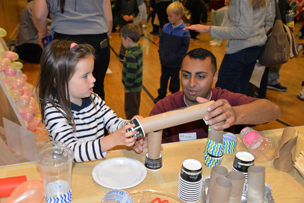 FOCUSED ON FUN — Sandia systems engineer Raheel Mahmood shows a student how to construct a roller coaster track for marbles.