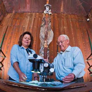 Image of <p>FIERY STUDIES - Sylvia Gomez-Vasquez and Walt Gill (both 1532), in the   burn chamber in Coyote Canyon, demonstrate the early stages of sample   analysis of crusty pieces of burned debris such as might occur after a   rocket propellant fire. Sandia signed a three-year contract with the Jet   Propulsion Laboratory (JPL), California Institute of Technology, with   funding from NASA, for a propellant fire modeling project. (Photo by   Randy Montoya) <a href="/news/publications/labnews/archive/_assets/images/12-27-07/fire_1260.jpg">View large image</a>. </p>