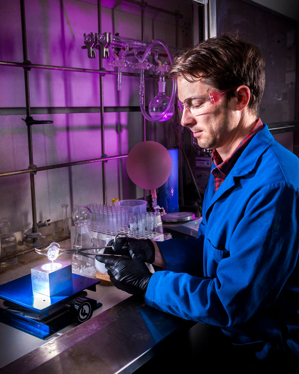 TOP GLASS — Materials scientist Joey Carlson demonstrates the ease of casting an organic glass scintillator. Casting the low-cost scintillator, which could be used in radiation detectors, takes only a few minutes as compared to other scintillators that can take several months. (Photo by Randy Wong)
