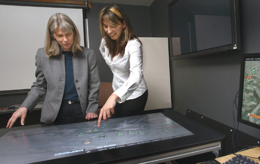 Donna Djordjevich (8116) describes the high-level model of border security to Jill Hruby, VP of the IHNS SMU and Div. 6000. The software provides a virtual environment where users can run various scenarios to see the outcome of their decisions. (Photo by Dino Vournas)