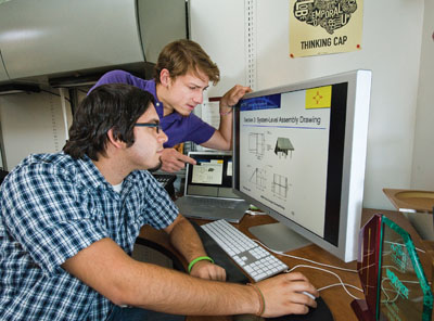 Austin Silva (1462), foreground, and Tyler Bushnell (6121) review the intricacies of their award-winning design. The concept is intended to serve as a life-saving solar-still desalinator device in the event of a natural or man-made disaster. (Photo by Randy Montoya)