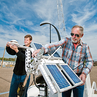 Image of <p>WEATHERWISE — Tim Leonard, right, owner of Precision Solar Technologies Corp., and the company’s project engineer, Tony Louderbough, do final adjustments on the instrumentation of a trailer-mounted solar weather station, called the Prospector Mule, at Sandia Labs. Precision Solar uses a tracking technology developed at Sandia. (Photo by Randy Montoya) <a href="/news/publications/labnews/archive/_assets/images/12-15-06/solartrak.jpg">View large image</a>. </p>
