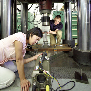 Image of <p>BREAK TIME — Helena Jin and Kevin Nelson (both8526) inspect the test setup for upcoming experiments to determine the breakingstrength of weapon case lugs. (Photo by Dino Vournas) <a href="/news/publications/labnews/archive/_assets/images/12-24-08/mech1000.jpg">View large image</a>. </p>