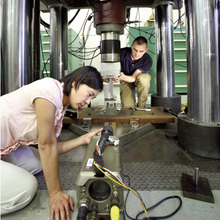 Image of <p>BREAK TIME — Helena Jin and Kevin Nelson (both  8526) inspect the test setup for upcoming experiments to determine the breaking  strength of weapon case lugs. (Photo by Dino Vournas) <a href="/news/publications/labnews/archive/_assets/images/12-24-08/mech1000.jpg">View large image</a>. </p>