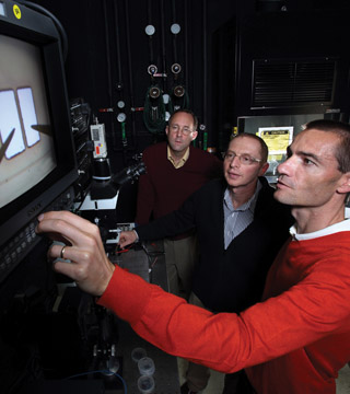 Mark Allendorf (8600), left, Alec Talin and Francois Leonard (both 8656) measure the conductivity of a MOF device, shown on the monitor (upper left). The team has developed a technique that increases the electrical conductivity of one MOF by more than six orders of magnitude.	(Photo by Dino Vournas)