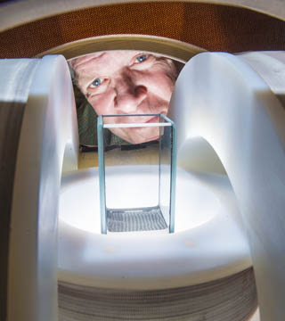 WATCHING PATTERNS FORM — Jim Martin (1114) peers between specially built magnets as he watches patterns form in a fluid inside a 3 cm glass container. Jim and doctoral researcher Kyle Solis have discovered how to harness magnetic fields to create vigorous, organized fluid flows in particle suspensions. (Photo by Randy Montoya)