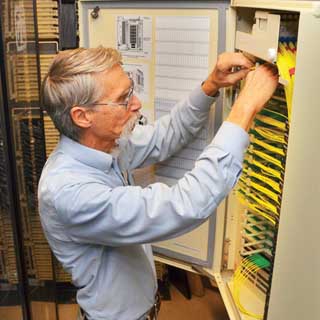 SENIOR ENGINEER Steve Gossage (9336) looks at fiber optics in a cable box that replaced heavier and bulkier copper cable for high-speed communications throughout much of Sandia. Fiber offers more capacity and is more reliable than copper. (Photo by Randy Montoya)