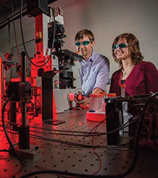 Sandia researchers Bryan Kaehr (1815) and Kristin Meyer (1815) analyze a silicized surface using optical microscopy and multiphoton fluorescence.	(Photo by Randy Montoya)