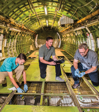Senior scientist Dennis Roach (6620), center, works inside the cabin of a B737 test bed installing and acquiring data from Structural Health Monitoring sensors with mechanical engineers Stephen Neidigk, left, and Tom Rice (both 6621).	(Photo by Randy Montoya)