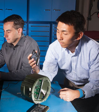 Stephen Downey (8135) and former Sandian TaiWen Ko evaluate adaptable telemetry hardware components as they build up the telemetry system to be used to test the Mark 21 replacement fuze. TaiWen is inspecting an environmental sensor measurement card of the telemetry system while Stephen modifies the firmware to be loaded onto the cardÕs field programmable gate array. Stephen and TaiWen are adjusting the hardware and firmware capability to increase bandwidth and hence provide more measurement capability of the W87 fuze and its environments during test flights.	(Photo by Randy Wong)