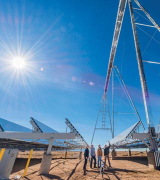 HOT SALT — A team of Sandia and AREVA engineers standing beneath a structure at the National Solar Thermal Test Facility examines the focal point of the sunlight reflected from the rows of mirrors on the ground to the top of the structure, where molten salt is flowing. The resulting heat is stored and used later when the sun is not shining. For more about this innovative solar energy project, see the story on page 4.		(Photo by Randy Montoya)