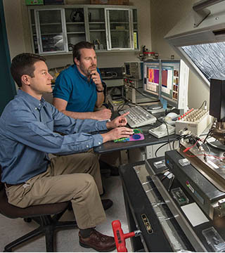 Researchers Jon Ihlefeld (1816), left, and David Scrymgeour (1728) use an atomic-force microscope to examine changes in a material’s phonon-scattering internal walls, before and after applying a voltage. The material scrutinized, PZT, has wide commercial uses. (Photo by Randy Montoya)