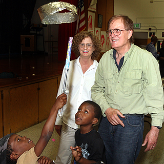 Image of JOANNE AND MARK PERRA look on as Ta’Jir Golden keeps a foil loop aloft with the mini Van de Graaff generator. In retirement, the couple has become very involved in science education in Oakland public schools. (Photo by Dino Vournas) <a href="/news/publications/labnews/archive/_assets/images/12-13-07/Perras1.JPG">View large image</a>.