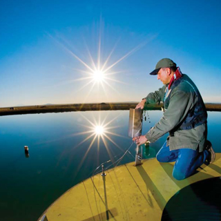 Image of <p>TECHNOLOGIST AT WORK — Richard Simpson (1384) places an acoustical sensor at a small lake Sandia built several years ago to do LNG fire tests on water. He has worked on numerous tests at the Labs in his 27-year career.           (Photo by Randy Montoya)</p>