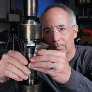 Image of <p>RESEARCHER TOM CRENSHAW (1831) sets up a specimen in a test frame that will pull the solder joint apart to determine its tensile strength. Tom co-authored a paper that won the Best of Proceedings category in the Surface Mount Technology Association’s International 2012 Best Papers conference.          (Photo by Norman Johnson)</p>
