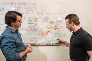 “Here, a miracle occurs!” — No, it’s just a series of equations and graphs describing Z, being batted about between Sandia’s Patrick Knapp (1688), left, and Paul Schmit (1684).	(Photo by Randy Montoya)