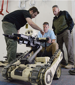 Image of <p>Bomb squad competitors from the Los Alamos Police Department prepare a robot before a scenario with an active shooter during sandia's annual Robot Rodeo.</p>