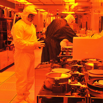 A Sandia process technician, left, and maintenance technician working one of the lithography bays of SandiaÕs Silicon Fab.  The Silicon Fab was recently accredited as a ÒTrusted FoundryÓ by DoD. (Photo by Randy Montoya)